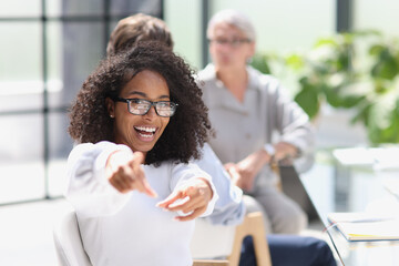 Young business woman sits at the table and rejoices in success