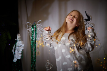 Small girl in the grey pajama posing int the room decorated for Christmas or New Year