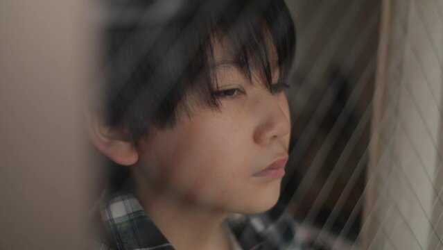 Japanese boy looks out of the window with emotion.