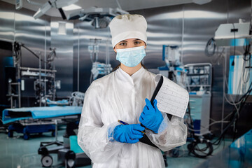 Fototapeta na wymiar doctor with stethoscope in operating room holding clipboard with operating room in background.