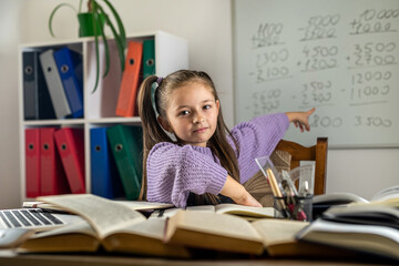 Portrait of a beautiful girl in the classroom at a desk with books and school supplies.