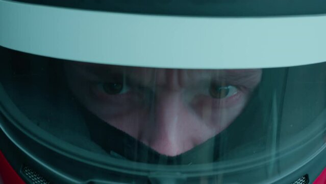 ECU Portrait of sports car driver in protective helmet racing on a speedway. Fast speed, motorsport. Daytime shot