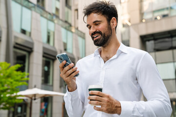 White man using mobile phone and drinking coffee at city street