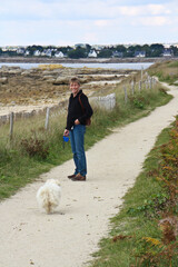 A woman walks with dog on the coast of Pont-l'Abbé