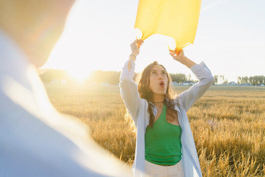 Woman with garbage bag standing at field on sunset