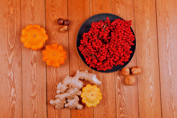 Still life with pumpkin- patison. Red viburnum berry, cranberry.Chicory root.Nuts. Autumn maple leaves.On a wooden background.meal.Thanksgiving day.the concept of fresh vegetables..place for text	