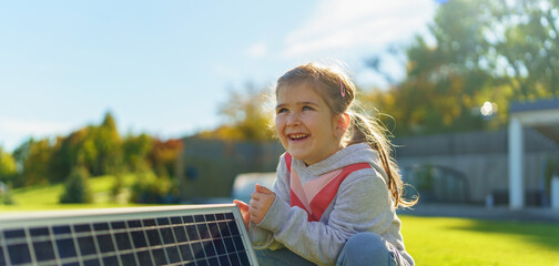 Little girl holding photovoltaics solar panel. Alternative energy, saving resources and sustainable...