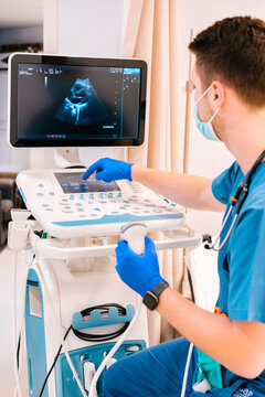 Young doctor examining and operating ultrasound machine at hospital