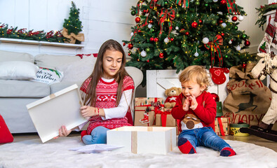 Obraz na płótnie Canvas Children open Christmas gifts under the tree. Selective focus.