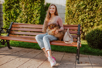 Smiling woman with dog sitting on bench in park