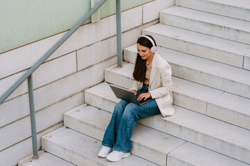 Young indian student woman in headphones working with laptop