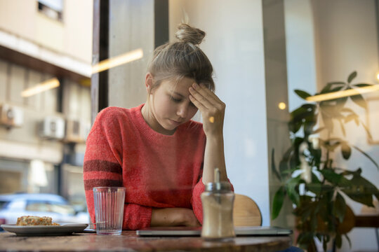 Tired freelancer sitting at table in cafe