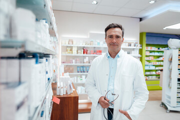 Man in lab coat holding stethoscope in pharmacy