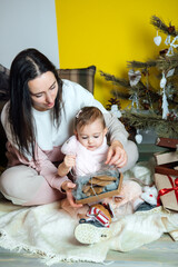 Boxing day and unpacking Christmas gift boxes. Cute Little baby toddler girl and mom unpack gift boxes near the Christmas tree at home. Merry Christmas and a Happy New Year