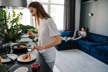 White young woman cooking breakfast while spending time with boyfriend