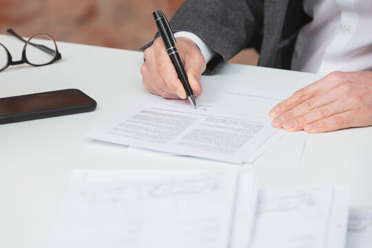 Hand of businessman signing contract with pen at desk