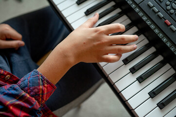Hand of boy playing synthesizer at home