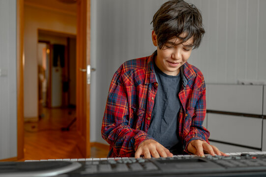 Smiling boy learning synthesizer at home