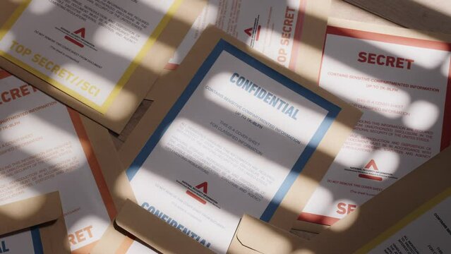 Pan over various color coded classified top secret documents and folders. Slow move on brown and yellow manila folders containing delicate and sensitive information. Government agency or leaked files