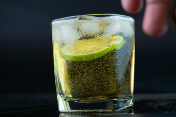 Shot of golden Mexican tequila with lime and salt on black background. A glass of tequila with lemon slices and splashing. Alcoholic drink concept. selective focus.