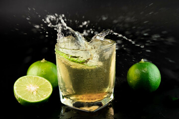 Shot of golden Mexican tequila with lime and salt on black background. A glass of tequila with...