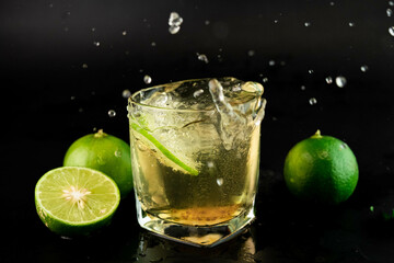 Shot of golden Mexican tequila with lime and salt on black background. A glass of tequila with lemon slices and splashing. Alcoholic drink concept. selective focus.