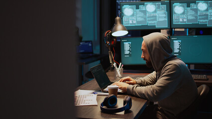 Dangerous coder hacking server to destroy information, breaking into corporate data servers using laptop and multiple screens. Trying to hack database and steal big data, cyberattack. Handheld shot.