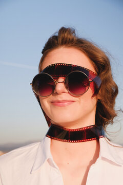 Funny portrait of a woman with sunglasses wrapped with photo film negative