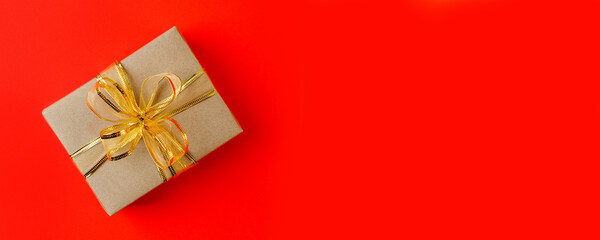 Craft gift box on red background, decorated with a textured bow, creating a romantic luxury atmosphere. For birthday, anniversary presents, gift post cards, banner, flyer, invitation, voucher