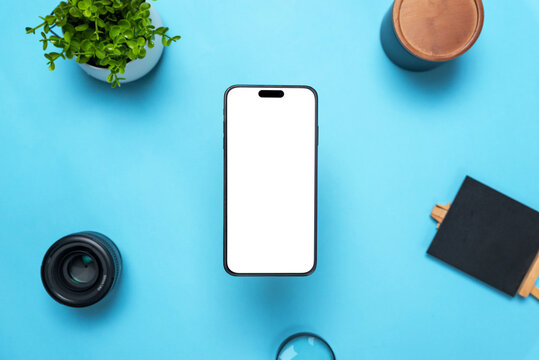 Phone mockup above a desk with objects around. Levitation above top view, flat lay composition. Isolated, transparent display for mockup, app user interface presentation