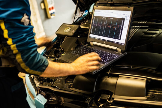 Mechanic perform chip tuning on tuned car in a garage workshop