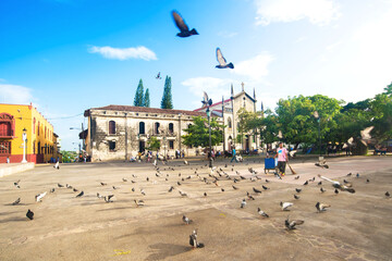 Beautiful view of the La Asunción school and chapel in the colonial city of León, Nicaragua. A calm happy morning in the Central Park of León. Pigeons flying in the blue sky over the city.