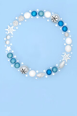 Magical Christmas wreath with tree bauble decorations on pastel blue background. Festive fantasy abstract concept for winter Xmas and New Year.