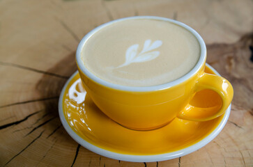 yellow cup of coffee on a wooden table
