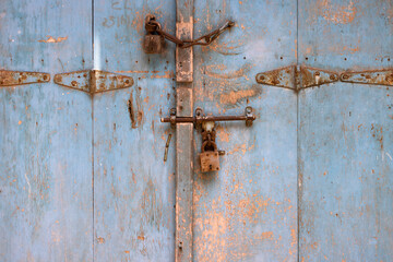 Puerta antigua de madera azul con cerrojos oxidados
