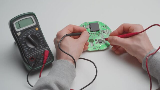 Man diagnosing a faulty circuit board with a multimeter. Medium close up