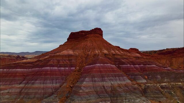 Aerial hyperlapse of storm clouds over rock formation with colorful sedimentary stripes in Southern Utah, USA
