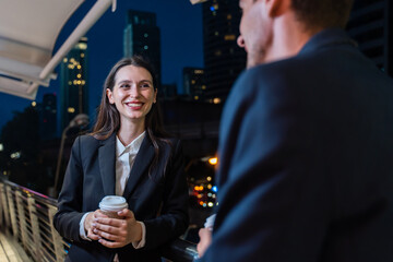 Caucasian young businessman and woman stand outdoor in city at night. 