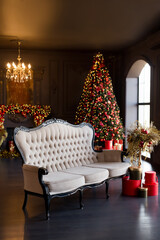 Interior of luxury dark living room with fireplace, comfortable sofa and chandelier decorated with Christmas tree and gifts