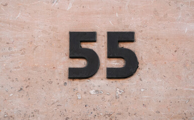 55 fifty-five house building number graved on a black marble concrete wall