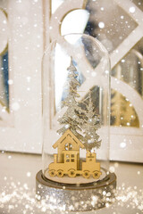 Beautiful snow globe and gift box on wooden table against blurred Christmas lights. Space for text