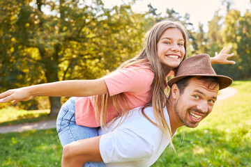 Happy father carries his daughter piggyback