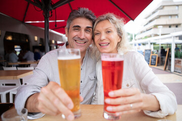 senior couple holding forwards their drinks on restaurant terrace