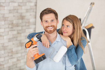 smiling loving couple doing home renovations holding tools