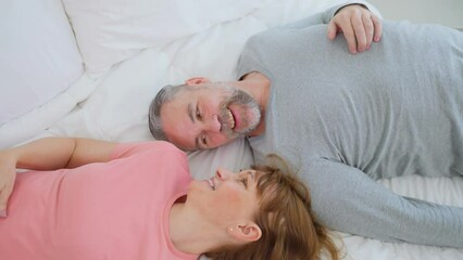 Caucasian senior older couple lying down on bed then look at each other - Powered by Adobe