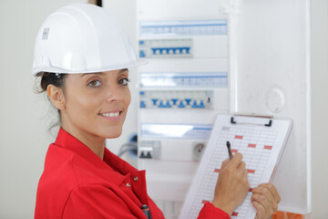woman with clipboard inspecting electrical box