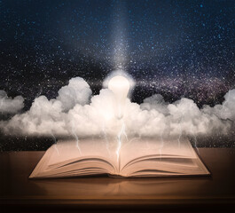 Open book with space and stormy sky. The included light bulb against the background of the starry sky and the book.
