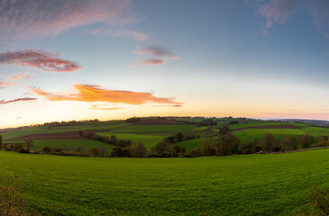 Spectacular and colourful sunrise over a rolling hill landscape with winding roads and agricultural fields in the south of Limburg. The landscape reminds of the Tuscan region in Italy.
