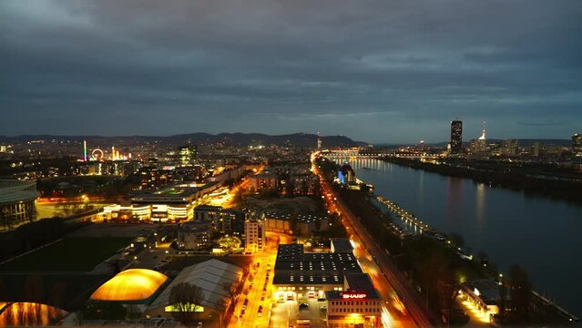 Aerial Timelapse of Illuminated Vienna City Danube Riverside Nightlife Traffic, Skyscrapers and Bridge Skyline with cloudy sky