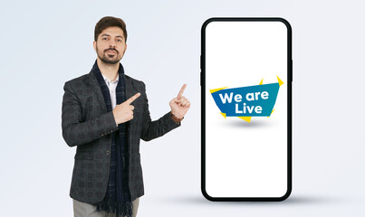 Mobile App Launch. Indian businessman in a suit and beard pointing towards the mobile screen....